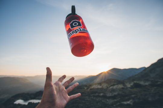 person throws away red water bottle