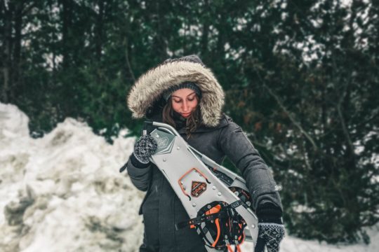 woman in black jacket holding white and red snow sled